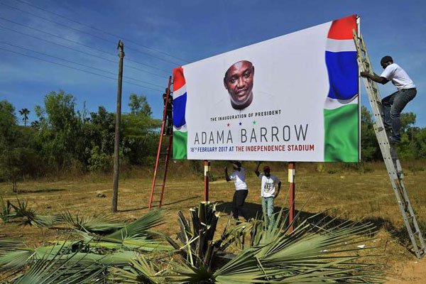 Workers erect a billboard to advertise the planned February 18 inauguration of Gambian President Adama Barrow in Banjul on January 26, 2017.