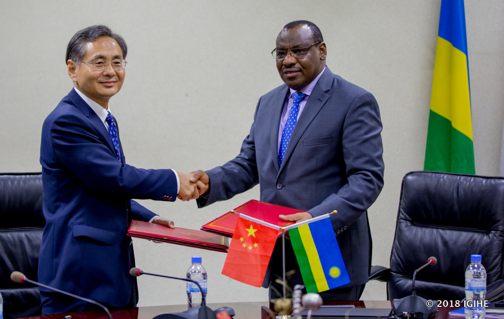 Minister Gatete and Ambassador Hoingwei exchange documents after signing the grant.