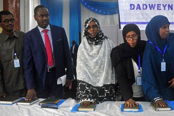 Members of Somalia's new federal Parliament place their hands on copies of the Koran as they are sworn in at the General Kahiye Academy in Mogadishu on December 27, 2016.