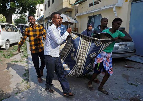 People carry a victim's body from the scene of a terror attack outside The Ambassador Hotel in Mogadishu on June 2, 2016. A resolution on Somalia adopted by the Security Council on July 7, 2016 dealt a setback to Kenya’s push for a UN takeover of the African Union Mission in Somalia (Amisom).