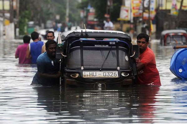 Sri Lankan flood victims push a trishaw through floodwaters in the Kolonnawa suburb of Colombo on May 21, 2016. Foreign aid began arriving in Sri Lanka on May 21, bringing help to half a million people forced out of their homes by heavy rains and landslides that have killed at least 71 in a week of extreme weather wreaking havoc in South Asia.