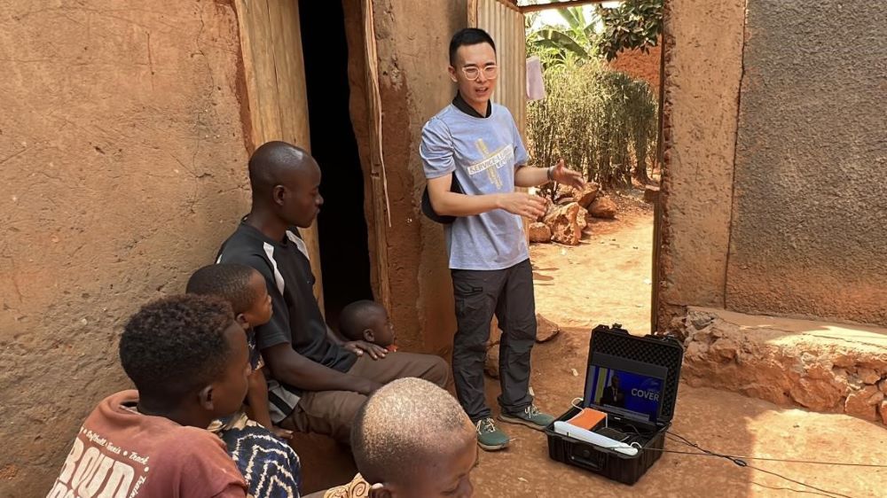 Dr Zhang Youqian, Teaching Assistant of the service-learning programme from the Department of Computing and a graduate of PolyU, introduces satellite TV to local villagers in Rwanda. (Photo by Su Ting)