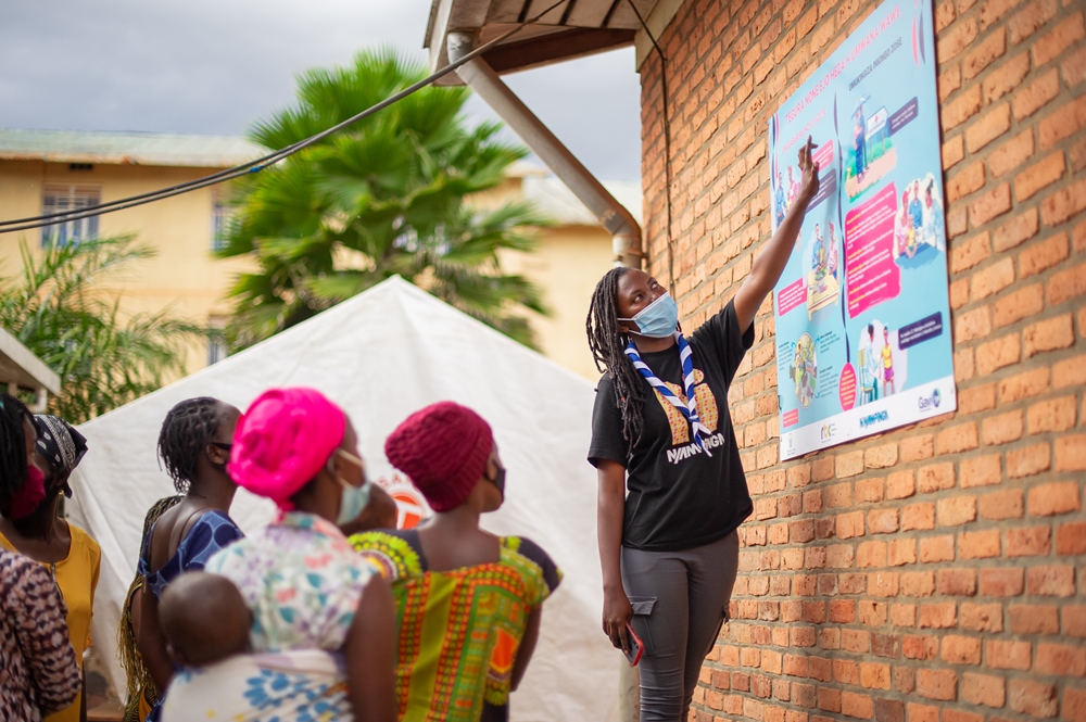 Ni Nyampinga ambassador with young mothers after hanging a wallpaper at a health center in Kicukiro district.