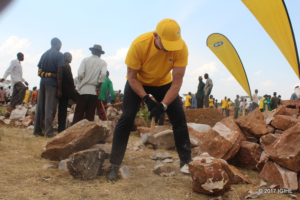 The CEO of MTN Rwanda, Bart Hofker shaping stones to be used during the construction of classrooms.