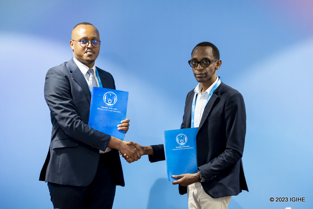 SPENN Country Manager, Karake Julius (left) and Gordon Kalema, the Director General of Digital Transformation at MINICT exchanging documents at the event.