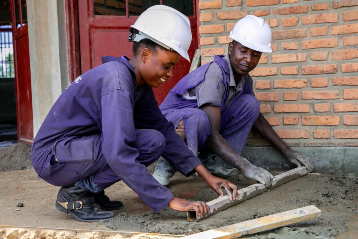 Donata, lead civil engineer in the construction of Rwanda's newest ECD centre, guides her employee to smooth a layer of cement