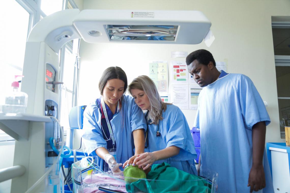Dr. Evelyn Little, center, and nurse Lizzy Smeaton-Russell, left, work with a new doctor at Gahini Hospital to care for a newborn resting in an incubator. Mentors like Evelyn and Lizzy spend six months mentoring doctors and nurses in Rwandan hospitals to help them build skills to better care for newborns.