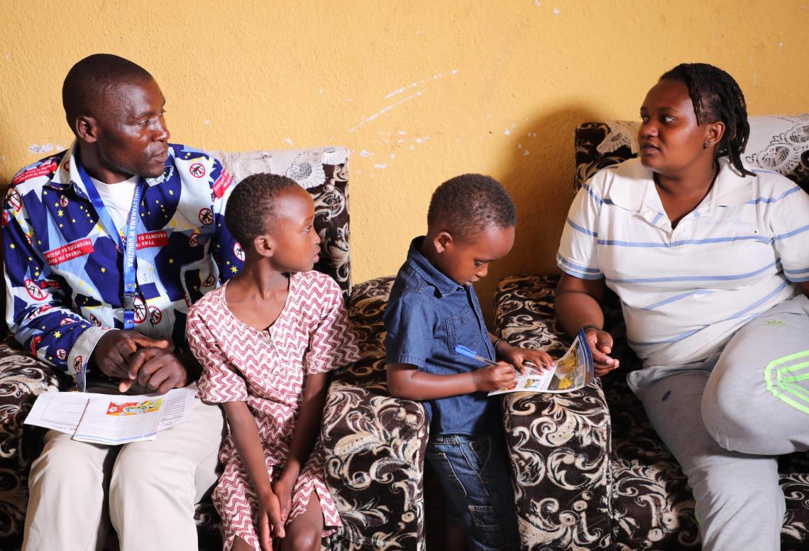 Daniel sits with a family in their home to discuss the signs and symptoms of Ebola and how people can prevent the disease from spreading.