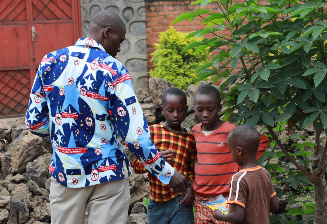 Daniel distributes leaflets on Ebola prevention measures, designed by UNICEF, to a group of boys in his community.