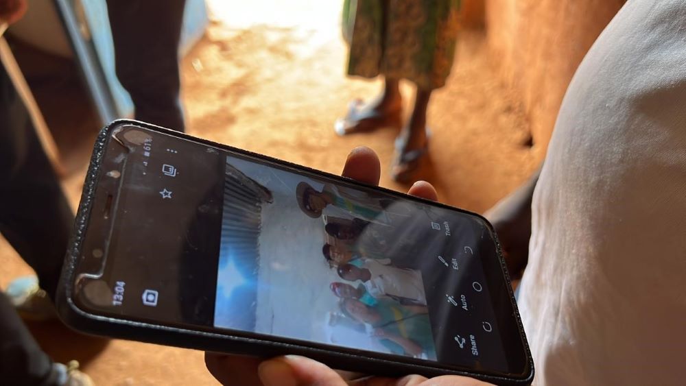 After lighting up his house, a local Rwandan villager takes a photo as a souvenir with the PolyU students who have helped him install the solar power system. (Photo by Su Ting)