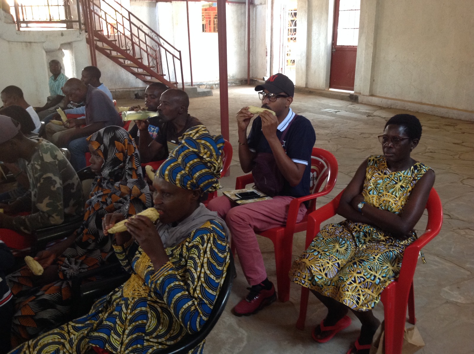 The writer (in a black cap and wearing glasses) enjoys boiled maize during Umuganura Day celebrations at a village hall meeting in Kigali on Friday, August 2, 2024.
