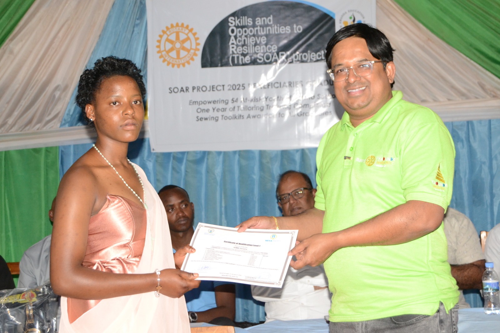 A graduate receives certificate from Rotary Club of Kigali Cosmopolitan leadership.