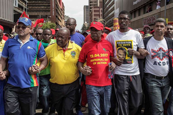 South African opposition parties leaders hold arms as they take part, with tens of thousands of opposition parties and civil society organization members, in a march to Union Buildings to protest against South African president Jacob Zuma and ask for his resignation, on April 12, 2017 in Pretoria, South Africa.